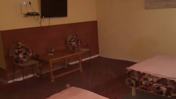 Una habitación con una cama, un escritorio, una silla, un televisor montado en la pared y un cuadro en la pared.