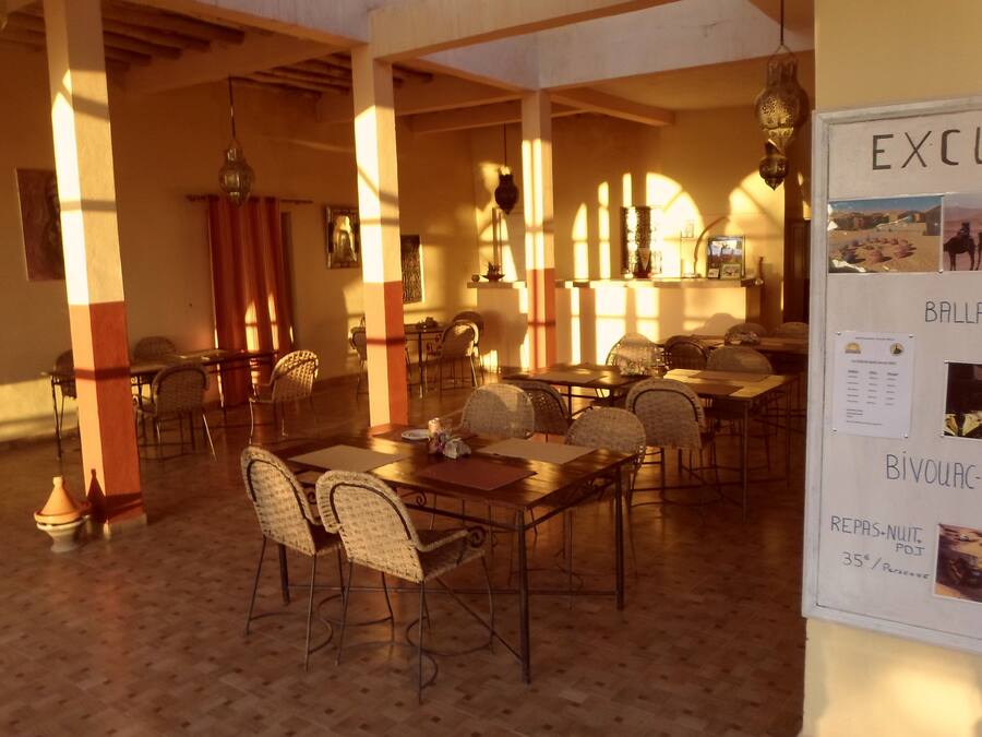 A dining area with tables and chairs, a bulletin board with excursion information, and a tiled floor.