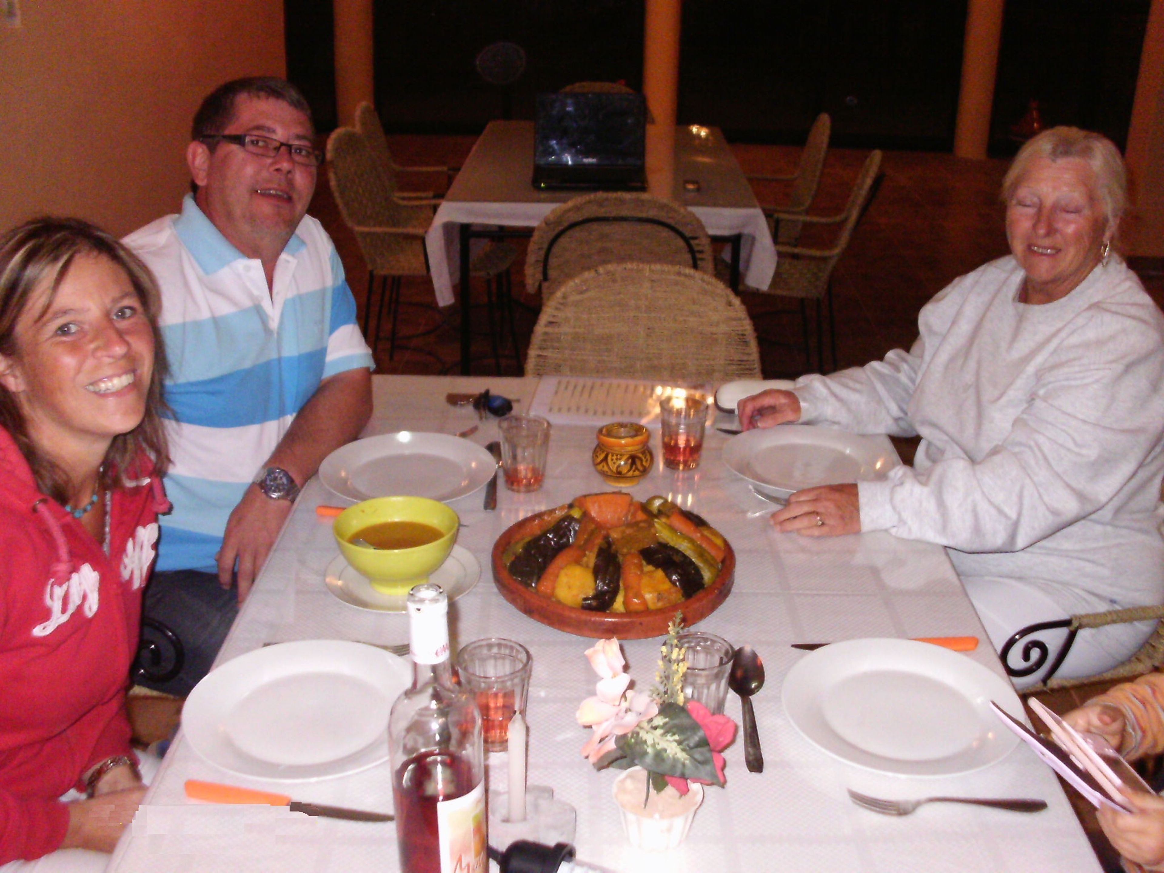 A dining table with plates, glasses, and a bottle of wine.