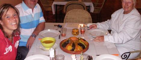A dining table with plates, glasses, and a bottle of wine.
