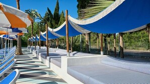A poolside area with lounge chairs and umbrellas, surrounded by palm trees. - BH Mallorca Apartments - Adults Only (Calvia)