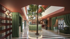 A hotel lobby with a central circular seating area, a palm tree, and a striped floor. - BH Mallorca Apartments - Adults Only (Calvia)