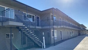 A multi-story building with a central staircase, multiple balconies, and a clear sky. - Regency Motel of Brea (Brea)