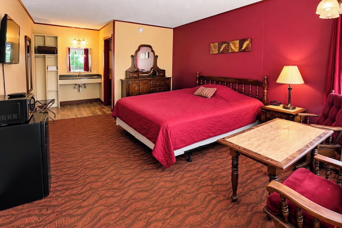 Een hotelkamer met een bed, een bureau, een stoel, een televisie, een spiegel en een raam.