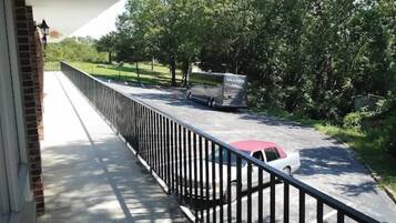 Un balcón con vistas a una calle, un coche estacionado y un autobús.