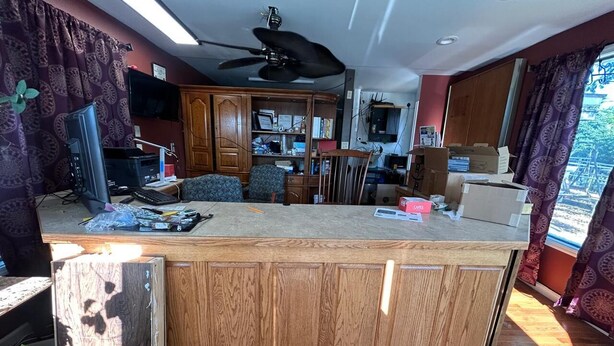 A kitchen with wooden cabinets, a central island, a ceiling fan, and a view of the outdoors.