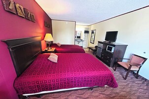 A hotel room with a large bed, a desk, a television, and a wardrobe.