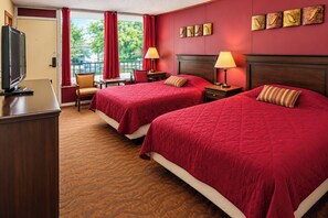 Een hotelkamer met twee bedden, een bureau, een televisie en een raam met gordijnen.