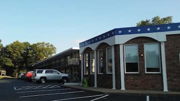 Un edificio con toldo azul decorado con estrellas, estacionamiento con espacios delimitados y fachada de ladrillo.