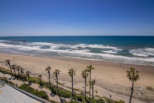 A beach with palm trees, a pier, and a clear blue sky.
