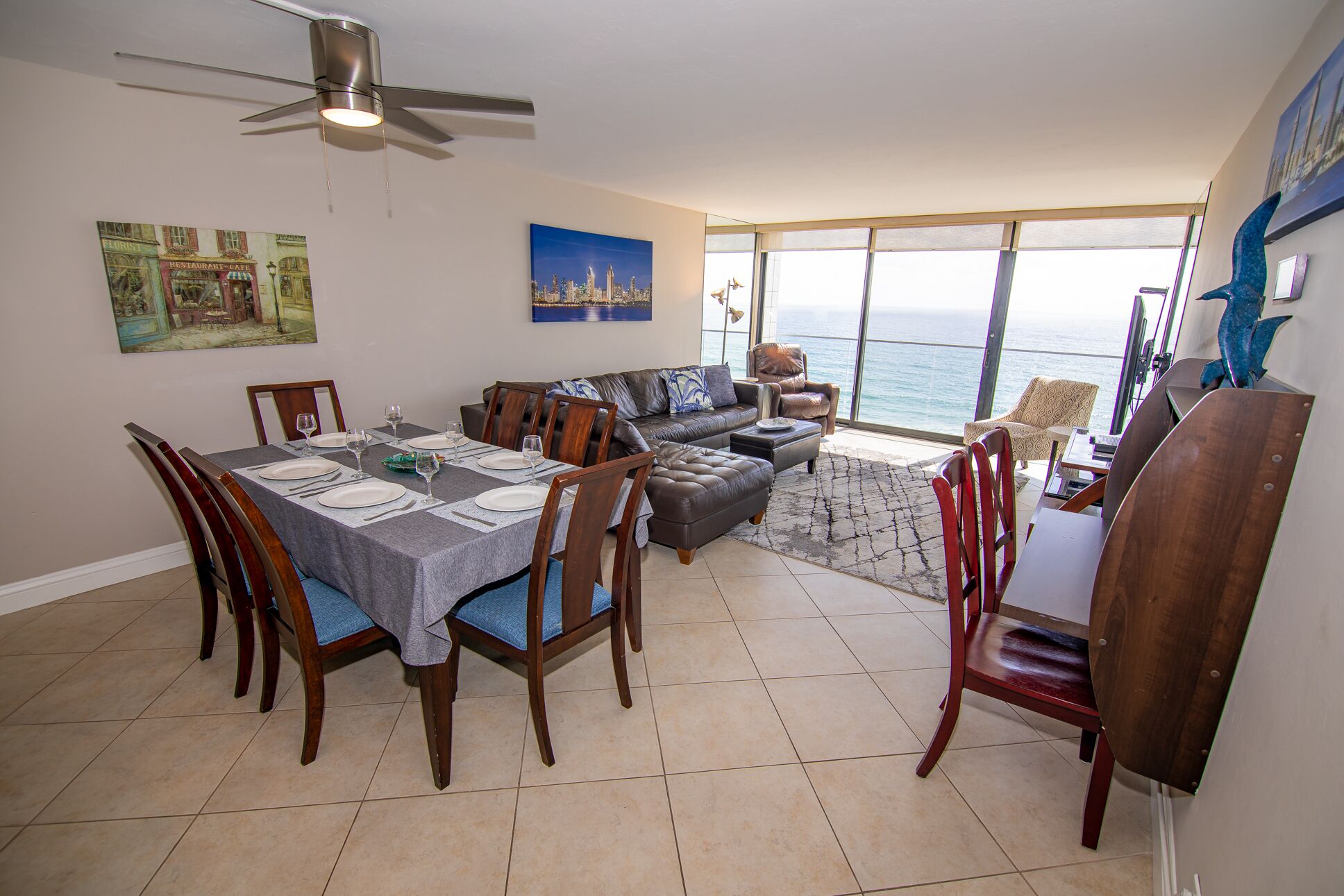 Un coin repas avec une table dressée pour quatre personnes, un canapé et une vue sur l’océan.