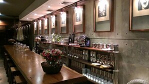 A long bar with a wooden countertop, shelves with glassware, and framed pictures on the wall. - Alfonsina Hotel Boutique by Inboccaluppo (Santa Cruz)