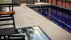 A modern outdoor pool area with a red brick wall, a large mural, and outdoor furniture. - Alfonsina Hotel Boutique by Inboccaluppo (Santa Cruz)