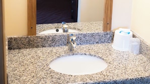 A bathroom with a granite countertop, a sink, and a mirror. - Stagecoach Inn (Molalla)