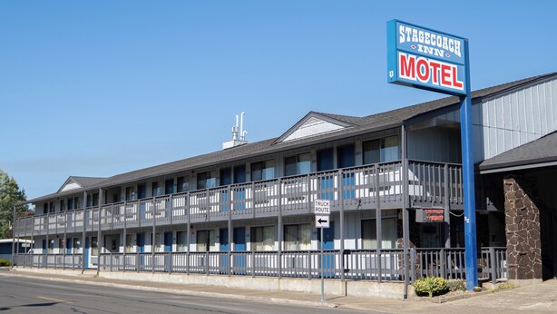 A motel with a blue sign, multiple windows, and a balcony. - Stagecoach Inn (Molalla)