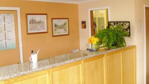 A kitchen with wooden cabinets, a granite countertop, and a vase with flowers. - Stagecoach Inn (Molalla)