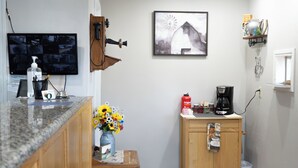 A small kitchen with a wooden cabinet, a coffee maker, and a vase with flowers. - Stagecoach Inn (Molalla)