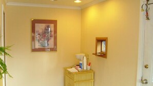 A hallway with a wooden cabinet, a framed picture, and a small window. - Stagecoach Inn (Molalla)