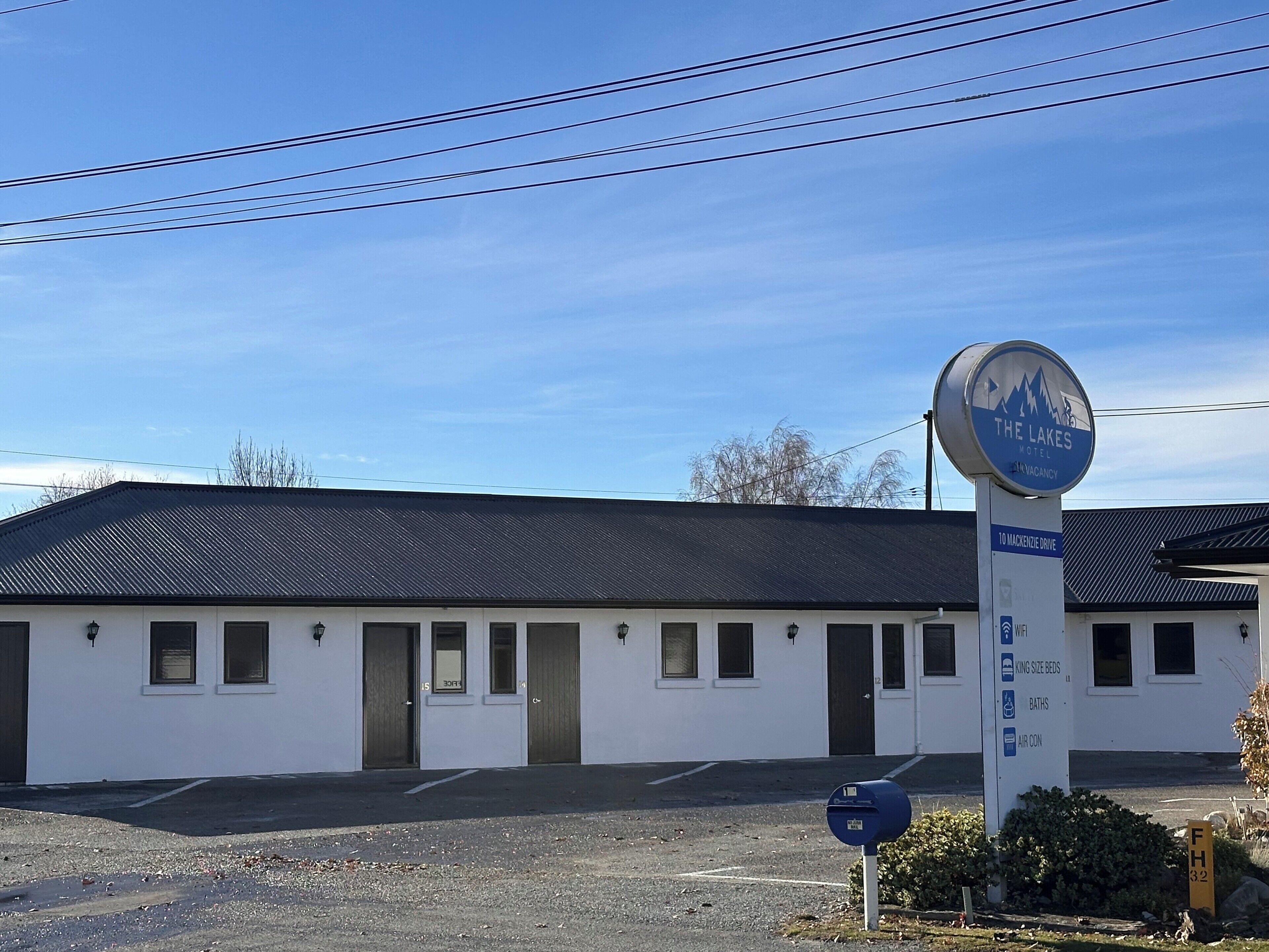 A motel with a sign indicating 10 MacKenzie Drive, a parking lot, and a signboard listing amenities like king size beds, baths, and air conditioning.