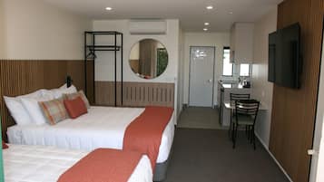 Una habitación de hotel con dos camas, un escritorio, una silla, un televisor y un espejo.