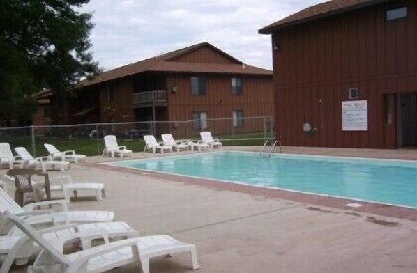 Une piscine avec des chaises longues et un bâtiment en bois en arrière-plan.