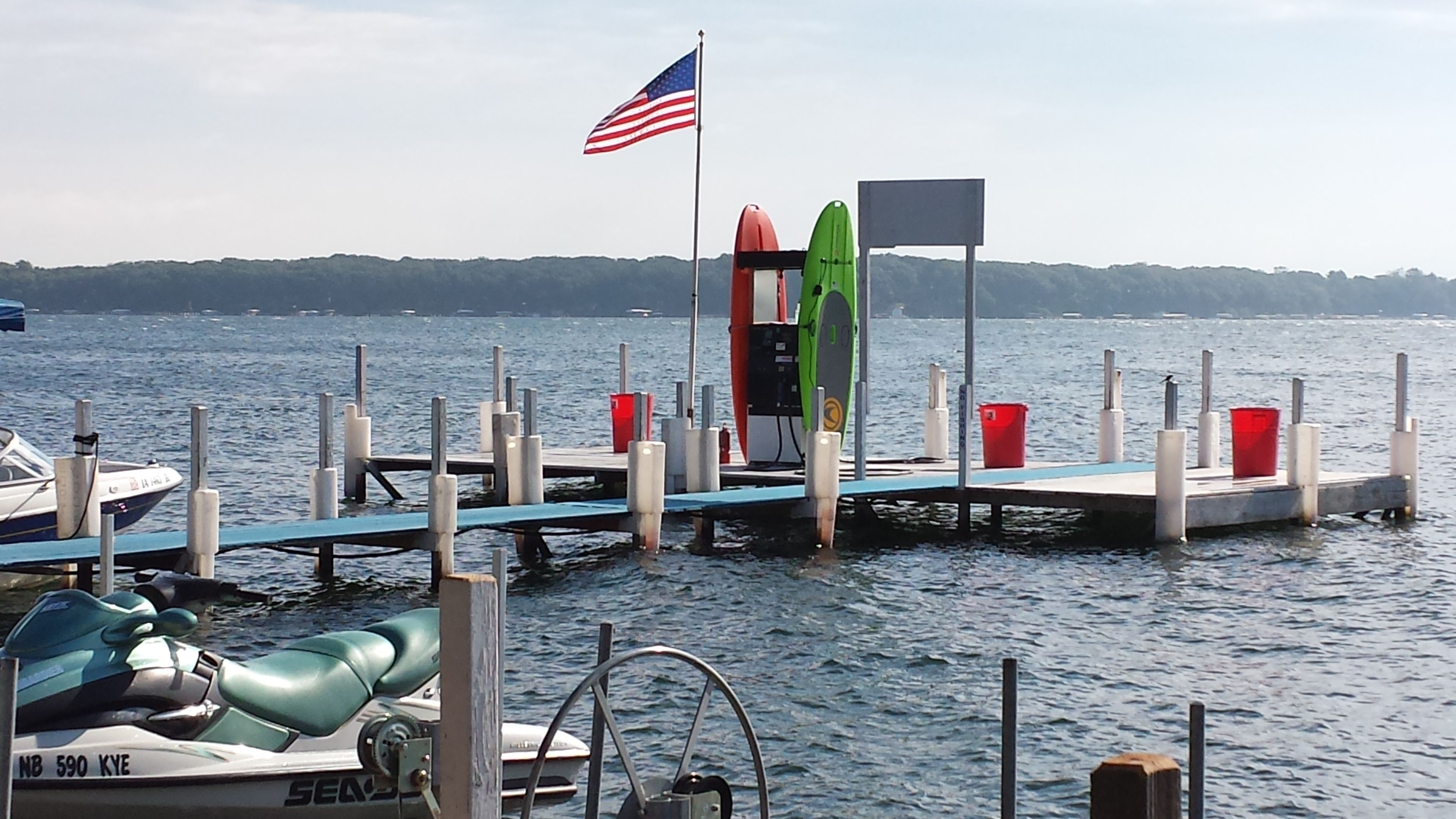 Un muelle con un jet ski, una tabla de surf y una bandera.