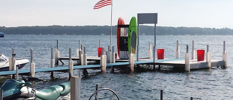 Un muelle con un jet ski, una tabla de surf y una bandera.