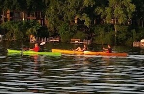 Trois canots sur une étendue d’eau calme, avec des arbres et un quai en arrière-plan.