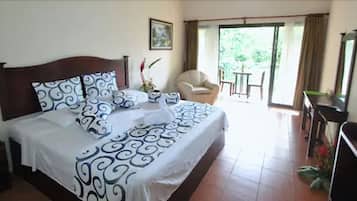 Habitación de hotel con una cama grande, una silla, un escritorio y vistas al exterior.
