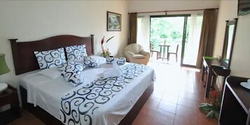 Habitación de hotel con una cama grande, una silla, un escritorio y vistas al exterior.