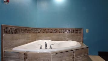 A bathroom with a freestanding bathtub, tiled walls, and a visible light switch on the wall.