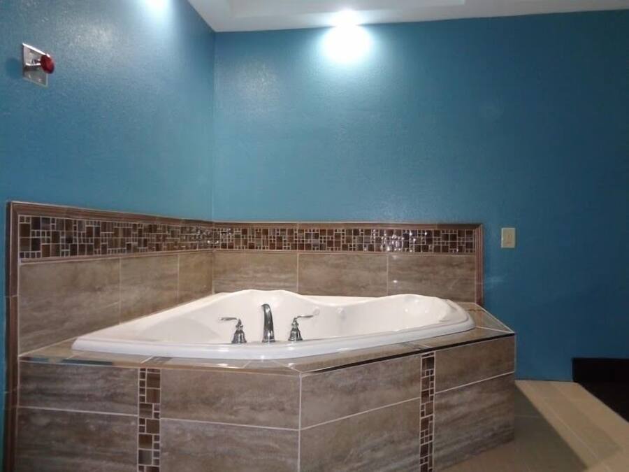 A bathroom with a freestanding bathtub, tiled walls, and a visible light switch on the wall.