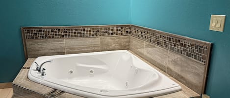 Un baño con una bañera independiente, paredes de azulejos y encimera de mármol.