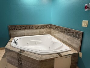 A bathroom with a freestanding bathtub, tiled walls, and a marble countertop. - Plymouth Bay Inn and Suites (Kingston)