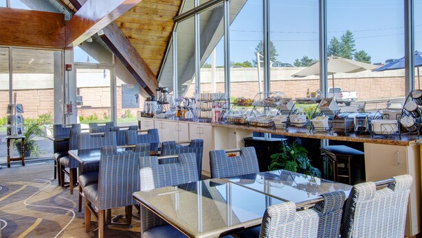 A restaurant with a glass dining area, wicker chairs, and a buffet counter with various food items. - Plymouth Bay Inn and Suites (Kingston)