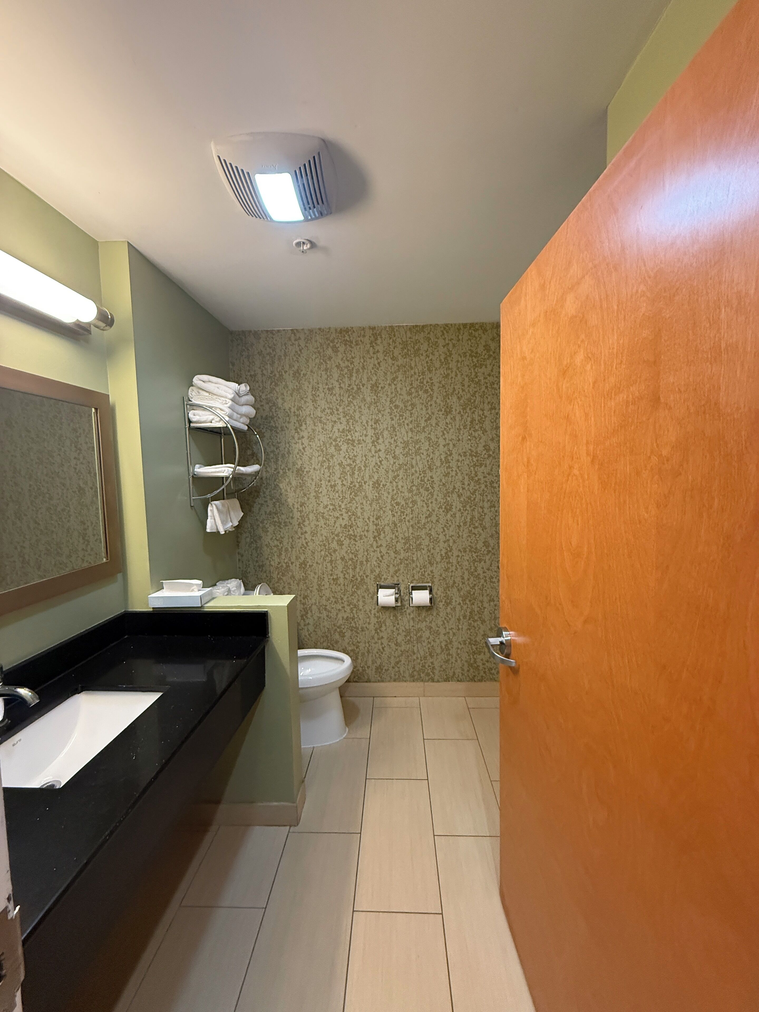 A bathroom with a black sink, white toilet, and a towel rack with folded towels.