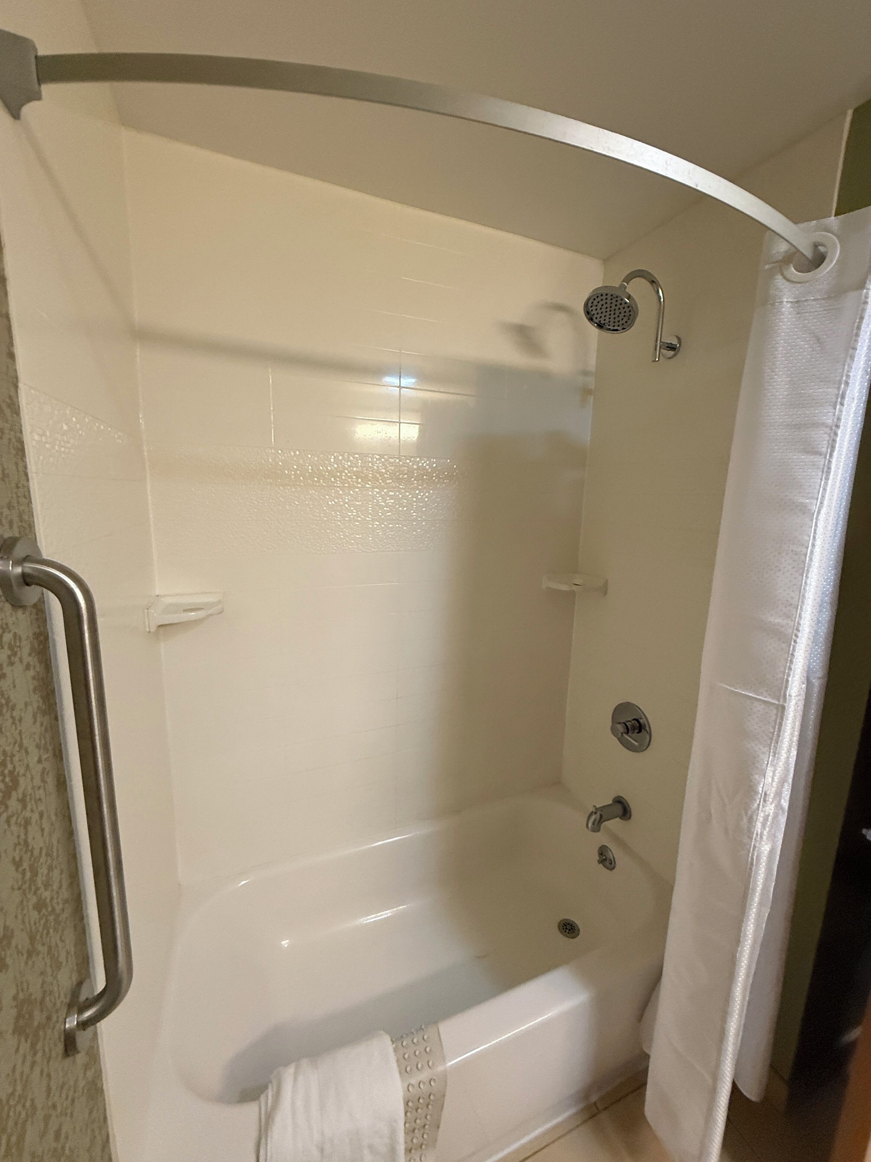 Un espace de douche doté d’une porte en verre incurvée, d’un pommeau de douche à main et d’un flexible de douche à main.