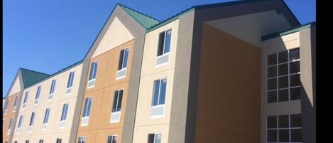 A multi-story hotel with a modern architectural design, featuring a flat roof and a series of windows on each floor.