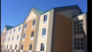 A multi-story hotel with a modern architectural design, featuring a flat roof and a series of windows on each floor. - Plymouth Bay Inn and Suites (Kingston)