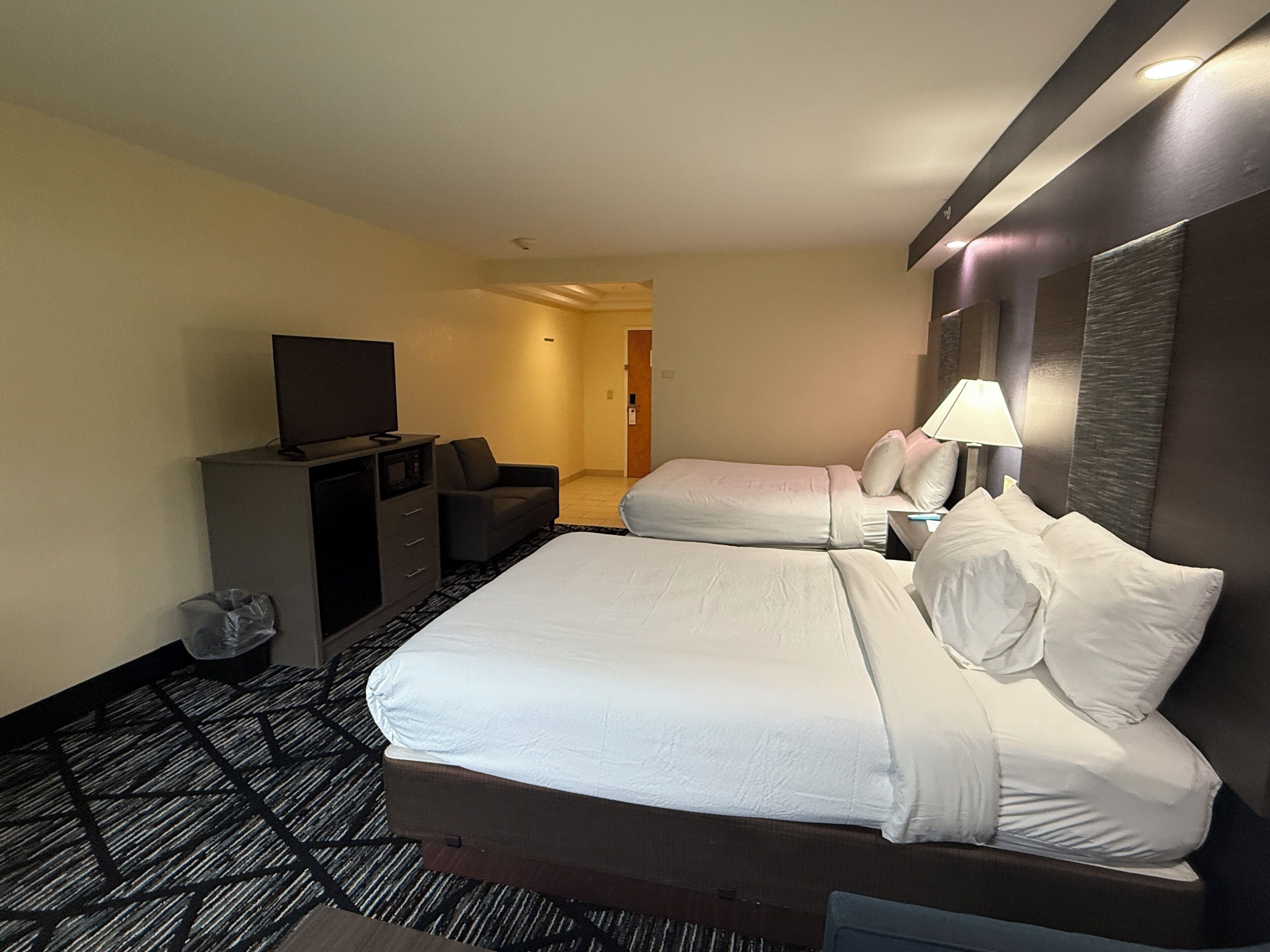 A hotel room with a large bed, a TV, a desk, and a chair.