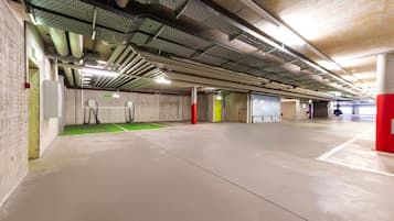 Eine großzügige Tiefgarage mit Betonböden und -wänden, Metallträgern und Lüftungskanälen.