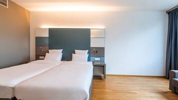Una habitación de hotel con una cama grande, una mesita de noche y una silla.