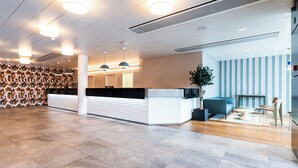 Een modern ingerichte receptie met een balie, zithoek en een behang met patroon.