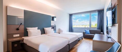 Una habitación de hotel moderna con dos camas, un escritorio y vistas a la ciudad.