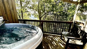 A hot tub on a wooden deck with a bench and a railing. - Eureka Zen Cottages (Eureka Springs)