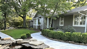 A residential property with a stone-lined pond, a well-maintained lawn, and mature trees. - Eureka Zen Cottages (Eureka Springs)