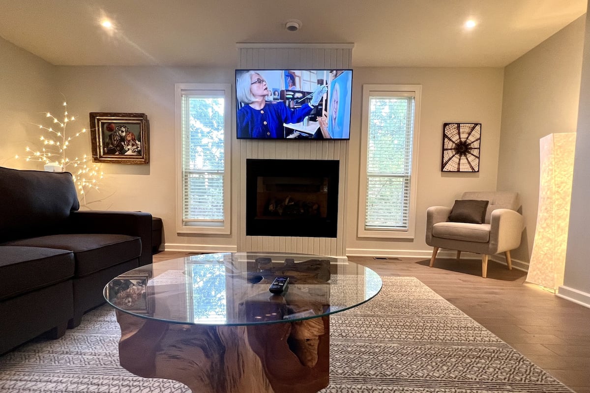 A living room with a glass coffee table, a fireplace, a television, and a sofa.