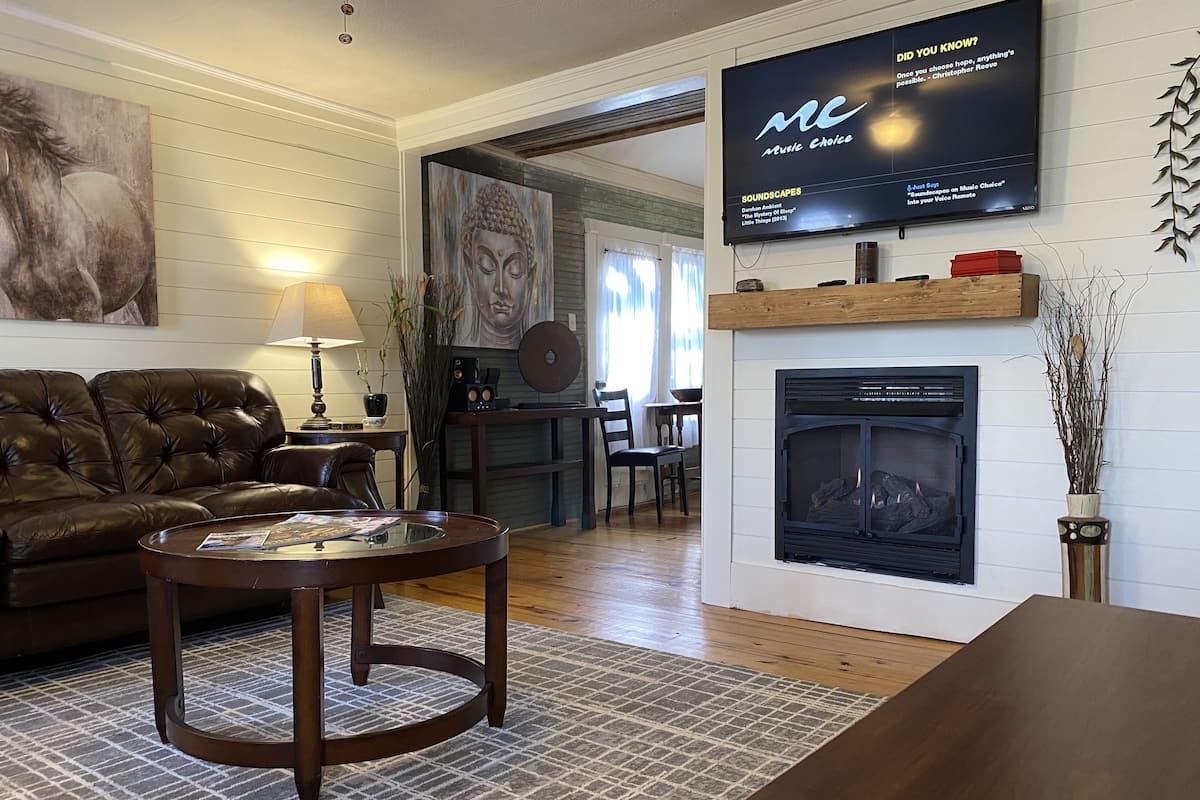 A living room with a leather sofa, a coffee table, a fireplace, and a television mounted on the wall.