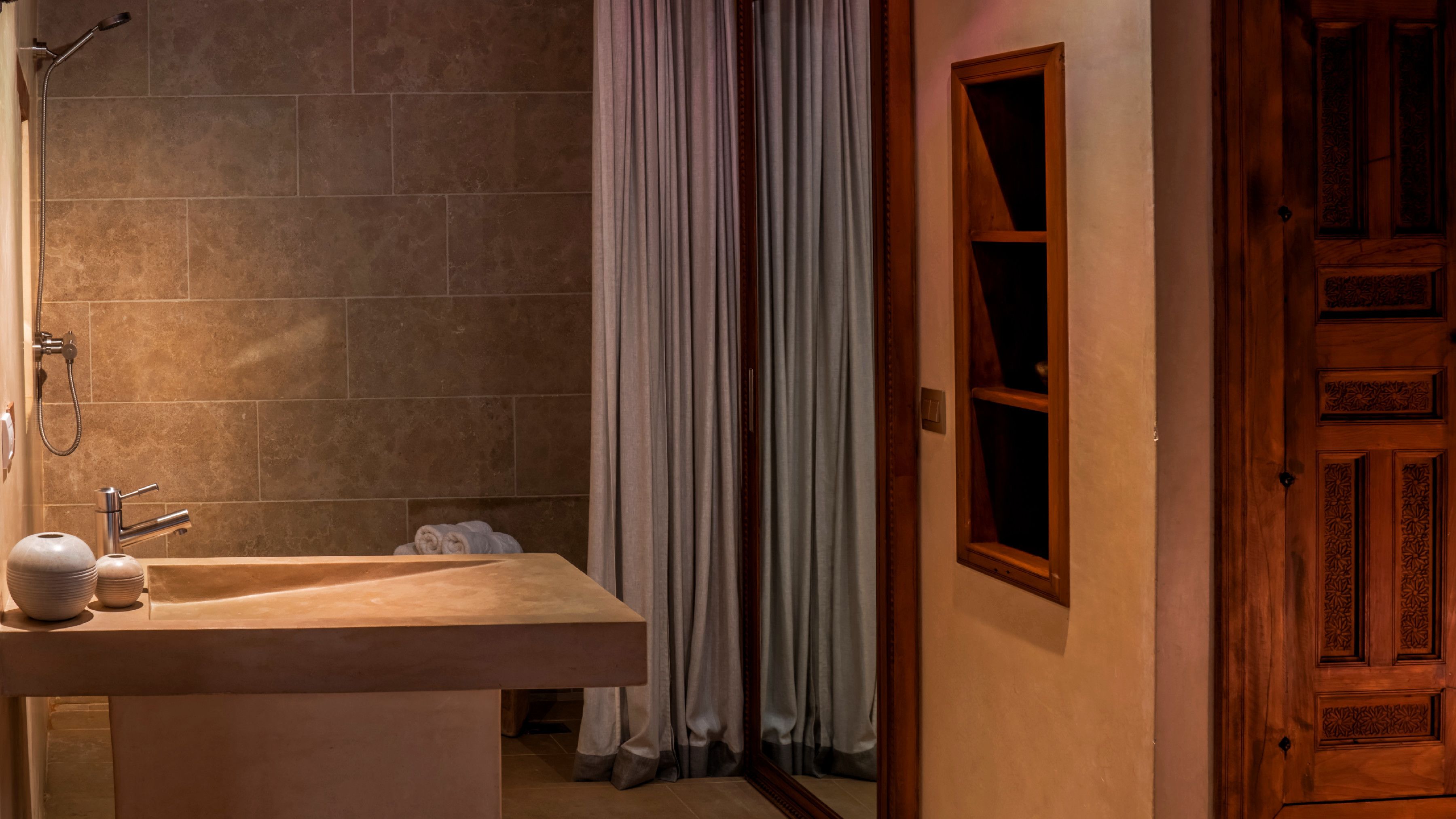A bathroom with a shower, a sink, and a wooden door.