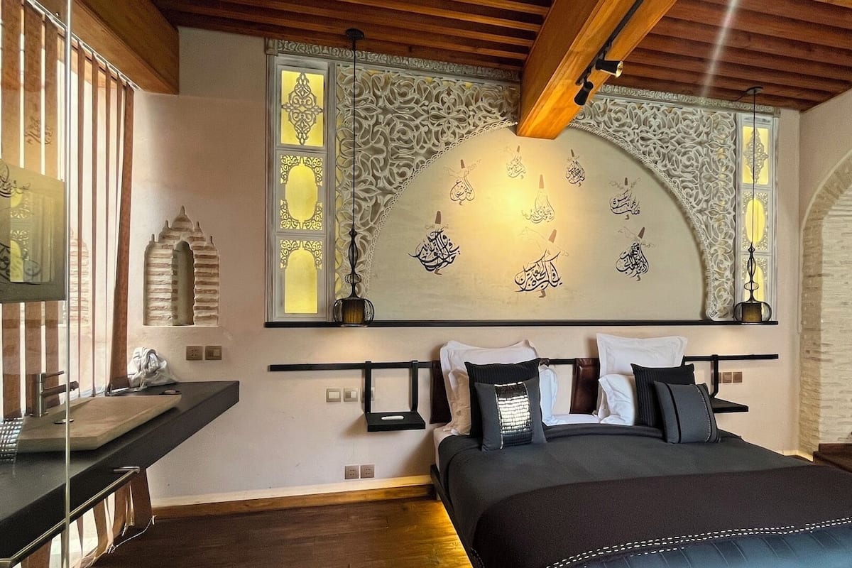 Ein Schlafzimmer mit Bett, Nachttischen, einem Schreibtisch und einem Fenster mit Dekoration.